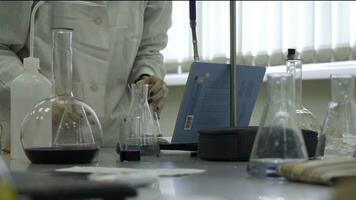 Lab technician doing experiment in lab. Male medical or scientific laboratory researcher performs tests with blue liquid. Scientist working with flasks in laboratory photo