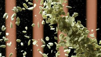 Close up of oat flakes falling down. Stock footage. Oatmeal splash, small flakes flying on black background with red vertical stripes, concept of healthy breakfast. photo