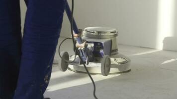 Man polishing marble floor in modern office building. Man works with grinding machine for floor photo