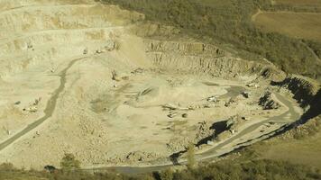 Top view of working quarry. Shot. Sand pit with escalators and buldozeri in open woodland. Mining concept photo