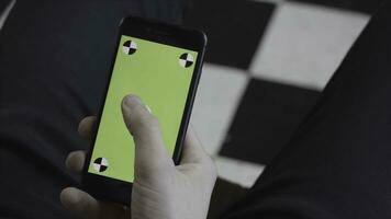 Man hands using mobile smartphone with green screen, over the shoulder view. Stock footage. Close up of man scrolling and tapping on Iphone screen with chroma key. photo