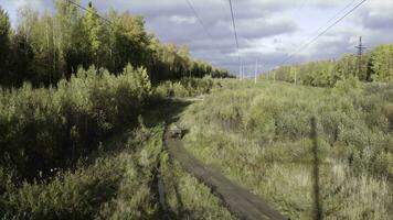 Top view of ATVs driving on off-road. Clip. Pair of military ATVs rides off-road in wooded area. ATVs ride on field road near autumn forest on sunny day photo