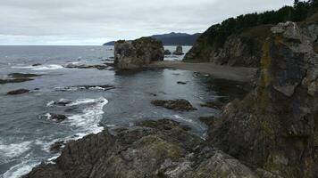 Top view of rocky coast with cliffs. Clip. Cinematic landscape with northern coast and cliffs. Rocky northern shore with green forests on cloudy day photo