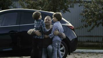 Father meets his little boys near his car outdoors. Stock. Concept of happy family and fatherhood. photo