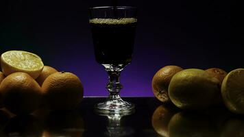 The concept of a bartender. Stock clip.Purple illuminated background with a large roomy glass in which soda is poured and the whole still life is decorated with light oranges photo