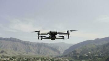 A drone flying over nature.Action. A small device for taking photos from a height in nature that shoots videos and spins in front of beautiful mountains in daylight.