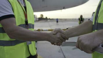 Employees in yellow dickey shake hands. Airport workers shakes hands. Engineers shake hands after checking. Airport workers photo