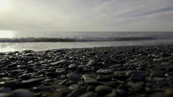 Pebble beach with small pebbles and sea waves. Action. Sea surface on the wild pebble beach, silent evening on the adriatic coast. photo