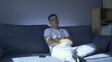 Young man is sitting on sofa and waiting for phone call. Media. Handsome young man is waiting for call sitting next to phone. Man is sitting on couch next to phone at home photo