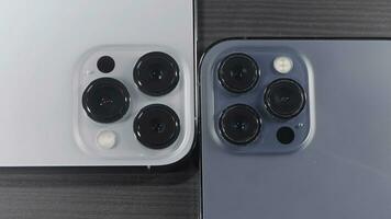 Saint Petersburg - Russia, 10.11.2021. close up of three cameras of new iPhone 13 pro max. Action. Stylish design and professional cameras of new blue and silver smartphones lying on wooden surface. photo