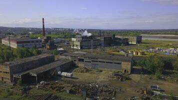 View of the work area from the drone. Clip. A large factory with pipes from which smoke is coming, the city and the forest and the calm sky are visible from behind. photo