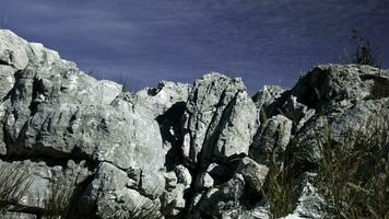 hermosa Roca acantilados creativo. grande montaña rangos en pie encima un azul soleado cielo siguiente a alto cañas . foto