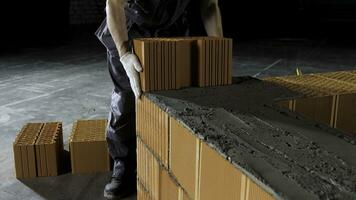 Industrial bricklayer worker placing bricks on cement while building walls. Stock footage. Close up of a man in protective gloves putting heavy brick block to form a layer. photo