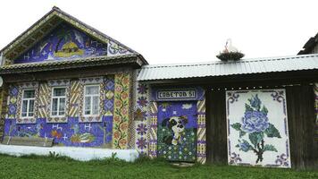 Unusual facade an old wooden house decorated by colorful mosaic pictures from small plastic bottle caps, creativity concept. Stock footage. Beautiful and bright hand made mosaic wall. photo