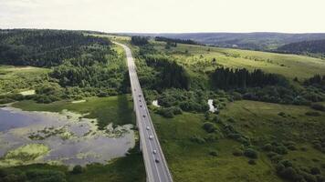 Aerial view over mountain road going through forest landscape. Clip. Beautiful landscape with mountain road with driving car and forest background. Sunset in the mountains. photo