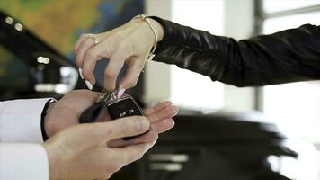 Woman hand with manicure, bracelet, and rings taking car keys from a man seller at the dealership. Stock. Salesman hand giving new car keys to a customer woman hand. photo