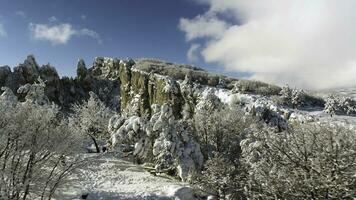 Fantastic winter landscape of high mountain and snowy forest on cloudy, blue sky background. Shot. Sunny day in white, winter rocks and trees covered with snow against bright sky. photo