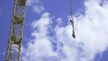 close up of a yellow and green crane boom with main block and jib against a clear blue sky. Tower building cranes against the sky photo