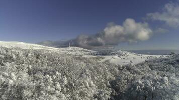 Fantastic winter landscape of high mountain and snowy forest on cloudy, blue sky background. Shot. Sunny day in white, winter rocks and trees covered with snow against bright sky. photo