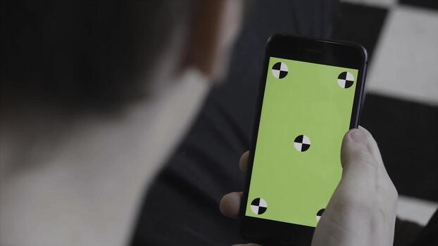 Man hands using mobile smartphone with green screen, over the shoulder view. Stock footage. Close up of man scrolling and tapping on Iphone screen with chroma key. photo