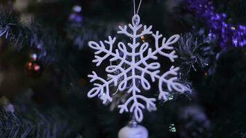 New year's toys on the Christmas tree like snowflake and red balls.New Year's decoration balls on a snowy branch. White snowflake and Blue Christmas ball. Selective focus photo