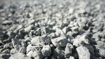 Background of gray granite gravel under the bright sun. Stock footage. Close up of white stones falling down on the ground, pebble texture. photo