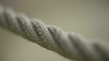 Extreme close up of a rope on blurred beige background. Action. Macro view of a stretched beige rope with a camera focus sliding slowly along the rope. photo