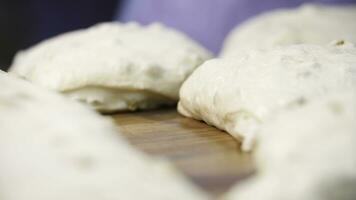 Close up view for raw pieces of pastry lying on the wooden board on the table. Stock footage. Traditional delicious pastry pieces with raisins ready for baking. photo