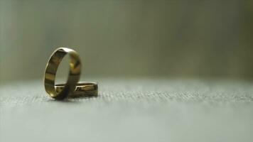 One gold wedding ring rolled to another. Video. Wedding rings. Two well used Golden Wedding Rings on gray background. Close-up bridal jewel of marriage. photo