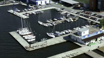 Aerial view of many white yachts and speed boats at harbor. Video. Sailing boats moored at the port in a city pond near parking on a summer sunny day. photo