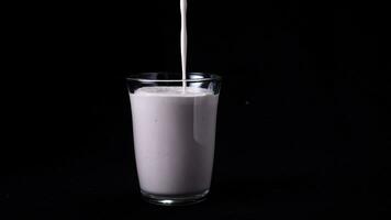 Strawberry milk shake isolated on black background. In transparent glass pour viscous pink milkshake on black background. Cool milkshakes photo