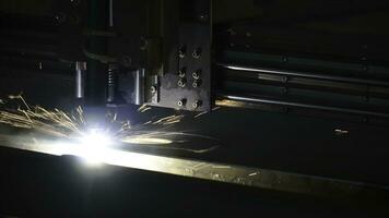 Laser cutter for manufacture. Clip. The laser cutter machine while cutting the sheet metal with the sparking light photo