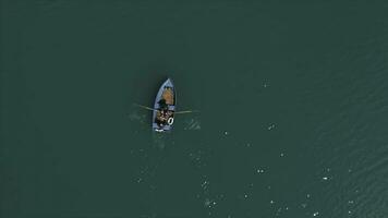 Aerial Boat on the lake. Aerial view on two men in a boat on a lake, rowed to the shore. Lonely boat in the middle of the river, lake. Boat single row on sea with reflection in the water in the photo