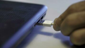 Man inserting usb cable into laptop. Media photo