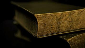 Close up of vintage thick book lying on flat surface isolated on black background. Stock footage. Side view of the edge of an ancient book with golden old pages. photo