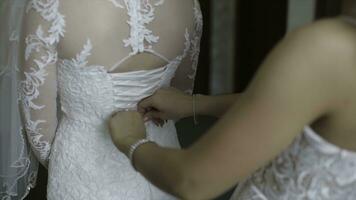 Mañana novia. dama de honor Ayudar el novia cordones arriba su vestido. novias ayuda el novia a sujetar un vestir foto