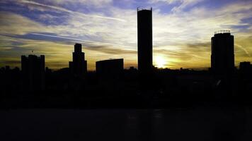 aéreo ver en hermosa vistoso dramático puesta de sol cielo terminado silueta de el ciudad. acortar. ciudad siluetas a puesta de sol con rascacielos antecedentes. puesta de sol en pueblo con negocio centros antecedentes foto