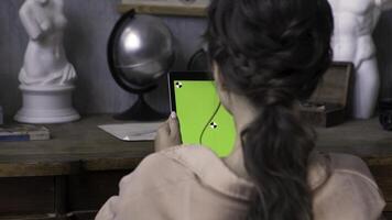 mujer manos participación tableta ordenador personal con verde pantalla en el Arte estudio con hormigón pared y plata globo, yeso mujer escultura en el de madera mesa. valores imágenes. niña tocando en chromakey tableta. foto