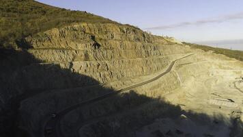 Top view of quarry with trucks. Shot. Multistage pit wall for mining and passing on her road for trucks and dumpers. Stepwise technology of extraction of stone photo