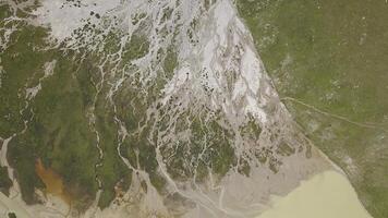 Terrain in mountains where meltwater flows. Clip. Top view of amazing lines on surface of mountains from flowing meltwater from glaciers. Muddy mountain rivers flow into lake photo