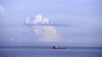 Cargo container ship sailing in still frozen summer sea on blue cloudy sky background. Shot. Red barge floating in blue sea on skyline background. photo