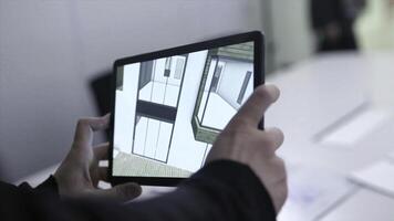 Virtual drawing of house on tablet. Stock. Businessman holding tablet with virtual reality project at home in boardroom. Digital 3D model of real estate project is shown on gadget photo
