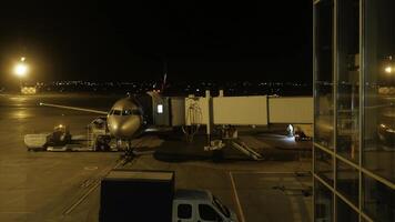 cerca ver de aeronave fuselaje cerca el entrando equipaje puerta, a noche. avión toma pasajeros lapso de tiempo foto