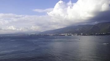 Aerial view of breathtaking blue ocean with small waves on coastal city background and mountains. Concept. Marine landscape with blue cloudy sky, concept of freedom and vacation. photo