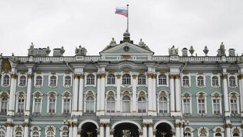 Facade of winter Palace with flag of Russia. Action. Greatest Russian architecture of Winter Palace in Saint Petersburg. Gold details and statues on turquoise facade of historic building in Russia photo