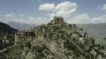 Ancient stone city on rock on background of mountains. Action. Amazing settlement of rock houses on top of mountain. Attraction of Dagestan - village of ghost in mountains photo