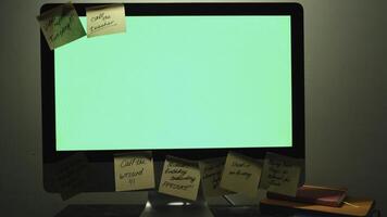 cerca arriba de moderno trabajando sitio con un chromakey pantalla computadora, diario planificadores y enviar eso notas concepto. hembra mano pegado un pegatina Nota en un computadora con verde pantalla. foto