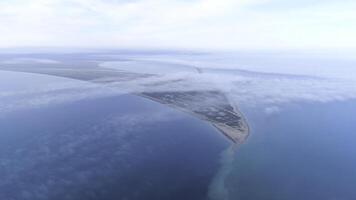 Top view of coast among sea on background of sky horizon. Shot. The highest view in sky among clouds on blue sea and triangular shore photo