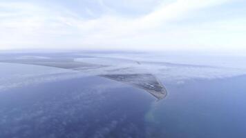 Top view of coast among sea on background of sky horizon. Shot. The highest view in sky among clouds on blue sea and triangular shore photo