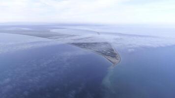 Top view of coast among sea on background of sky horizon. Shot. The highest view in sky among clouds on blue sea and triangular shore photo